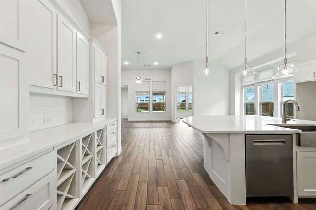 Kitchen with dark tile style flooring, dishwasher, white cabinetry, light countertops, and recessed lighting | Image 4