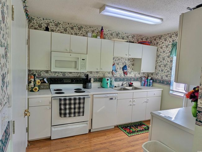 Kitchen featuring sink, white cabinets, white appliances, and light wood-type flooring | Image 5