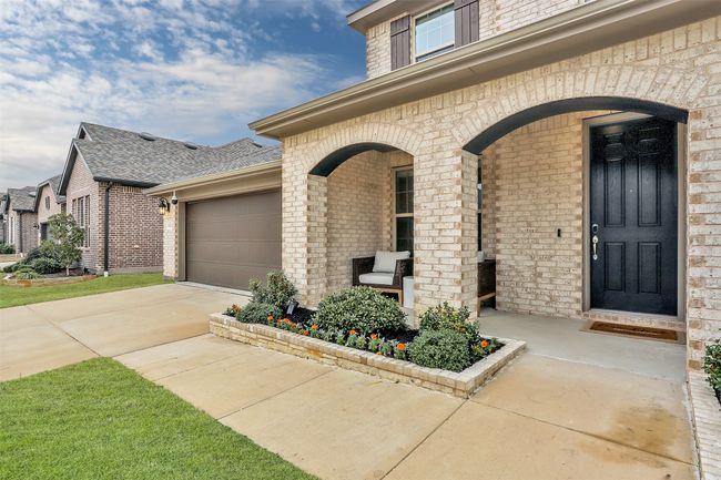 Entrance to property featuring brick siding, covered porch, driveway, an attached garage, and roof with shingles | Image 30