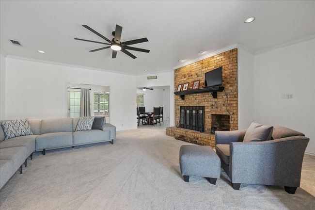 Carpeted living room featuring a ceiling fan, ornamental molding, a fireplace, and recessed lighting | Image 8