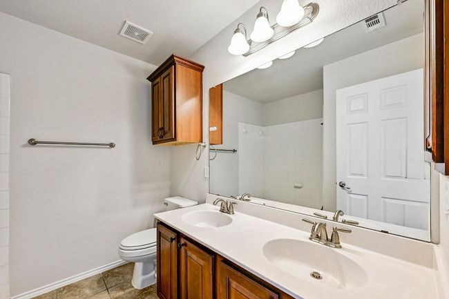 Bathroom with double vanity, a tile shower, and tile patterned floors | Image 21