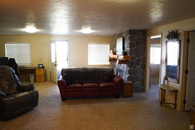 Carpeted living area with a textured ceiling and a stone fireplace | Image 18