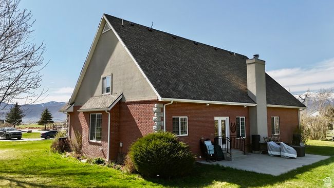 Back of house featuring a lawn, a patio, brick siding, a chimney, and a mountain view | Image 14