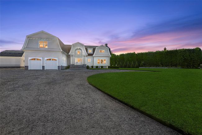 View of front of property featuring a gambrel roof, gravel driveway, an attached garage, and a front yard | Image 43