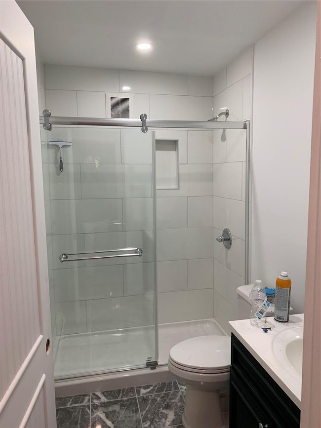 Bathroom with a stall shower, vanity, toilet, marble look tile flooring, and recessed lighting | Image 7