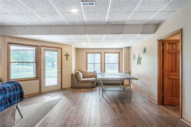 Recreation room featuring a paneled ceiling, baseboards, visible vents, and wood finished floors | Image 61