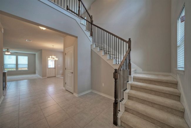 Stairs with tile patterned flooring, a towering ceiling, ceiling fan with notable chandelier, and baseboards | Image 5