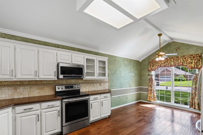At the heart of the home is a spacious kitchen showcasing stunning quartz countertops, chic glass-front cabinets and a large breakfast room perfect for casual dining. | Image 4
