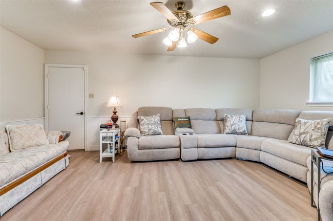 Living area with wood finished floors, a ceiling fan, a textured ceiling, and recessed lighting | Image 5