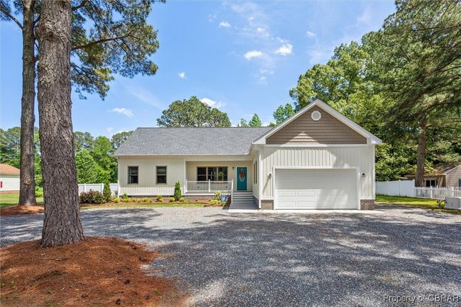 Ranch-style home featuring a porch, a garage, fence, board and batten siding, and gravel driveway | Image 4