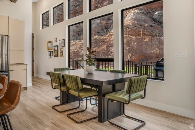 Dining space featuring light wood-style flooring, a high ceiling, and baseboards | Image 12