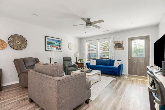 Living room with visible vents, a ceiling fan, baseboards, and light wood-style floors | Image 6