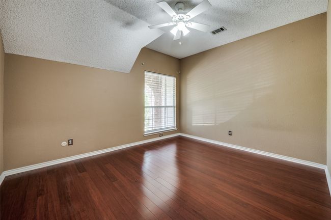 Spare room featuring wood finished floors, a textured ceiling, ceiling fan, baseboards, and visible vents | Image 26