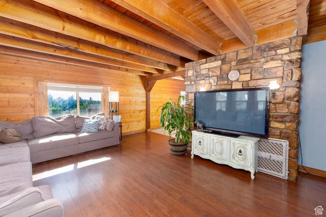 Living area featuring beam ceiling, wooden ceiling, wood finished floors, wooden walls, and baseboards | Image 18