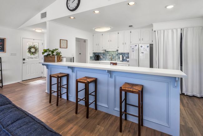 Kitchen featuring visible vents, freestanding refrigerator, white cabinets, light countertops, and dark wood-style flooring | Image 11
