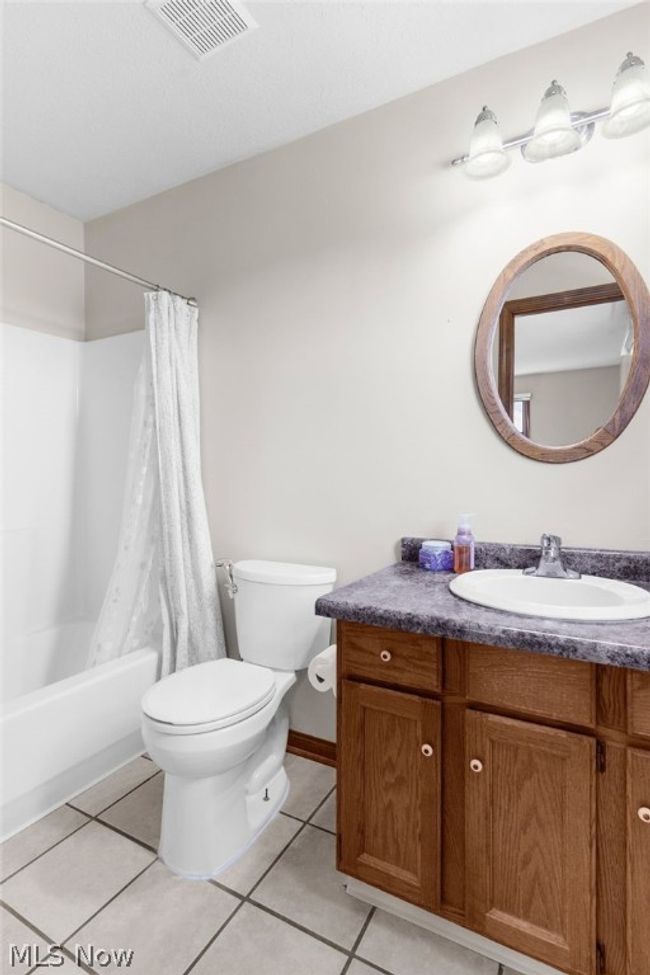 Full bathroom featuring tile floors, shower / bath combination with curtain, vanity, and toilet | Image 19