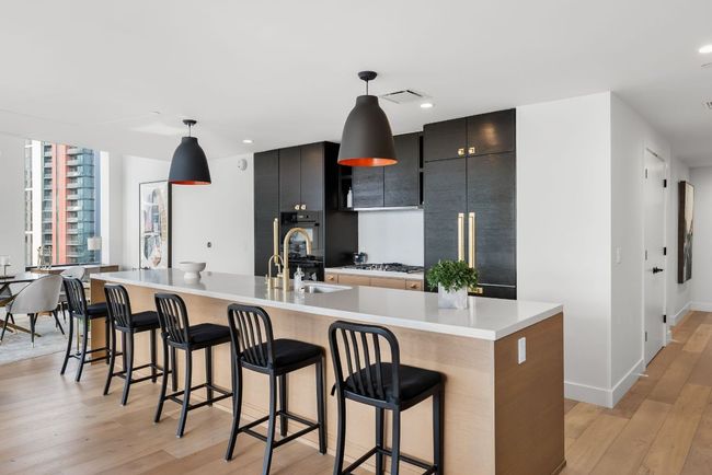 Stunning open kitchen featuring built-in Miele appliances, a gas cooktop, wine fridge, all overlooking the downtown views. | Image 11