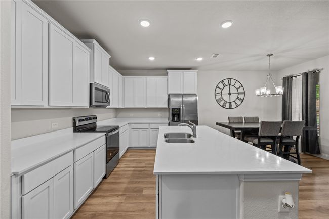 Kitchen featuring stainless steel appliances, a sink, an island with sink, a chandelier, and recessed lighting | Image 17