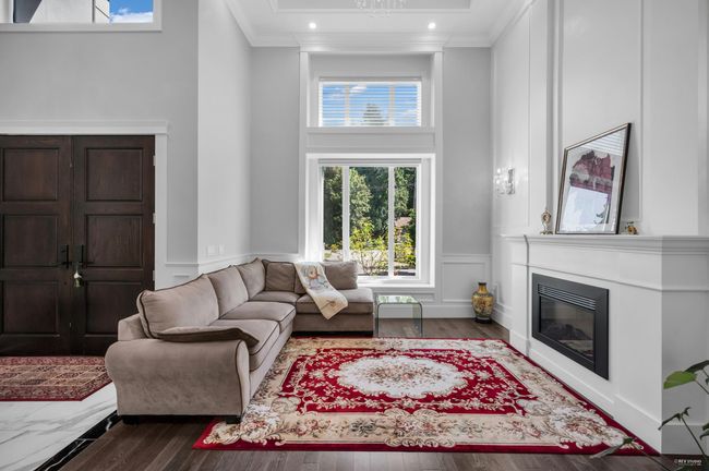 Living area with a wainscoted wall, crown molding, a glass covered fireplace, a decorative wall, and dark wood-type flooring | Image 4