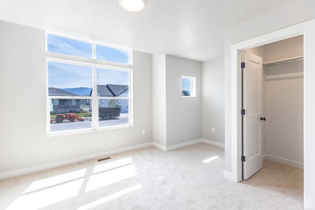 Unfurnished bedroom featuring light colored carpet, a walk in closet, and baseboards | Image 17