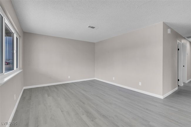 Unfurnished room featuring visible vents, wood finished floors, and a textured ceiling | Image 7