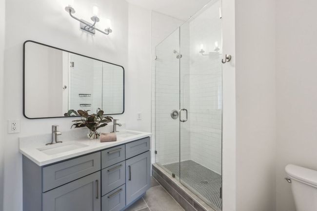 Full bathroom featuring toilet, a stall shower, double vanity, and a sink | Image 13