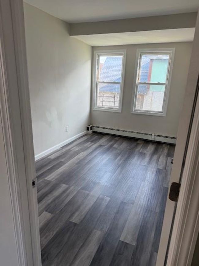 Empty room featuring a baseboard heating unit and dark wood-style floors | Image 14