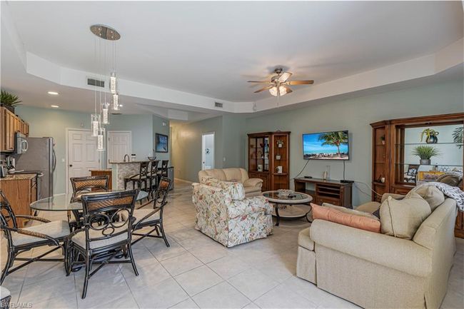Living area featuring a tray ceiling, a ceiling fan, visible vents, recessed lighting, and light tile patterned flooring | Image 6