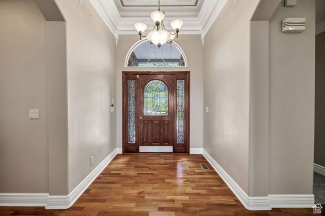 Foyer entrance featuring a chandelier, arched walkways, wood finished floors, a raised ceiling, and ornamental molding | Image 4