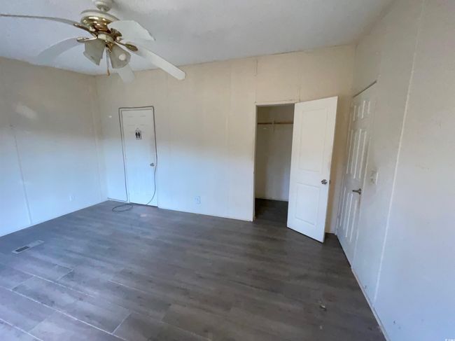 Unfurnished bedroom with visible vents, a closet, a ceiling fan, and dark wood finished floors | Image 20
