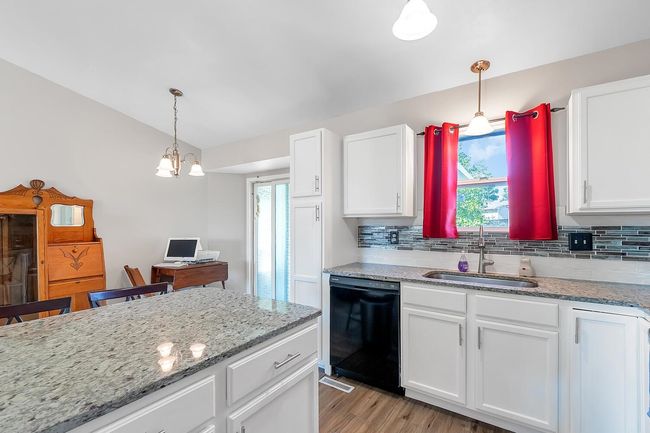 Kitchen with black dishwasher, tasteful backsplash, healthy amount of natural light, and white cabinetry | Image 14