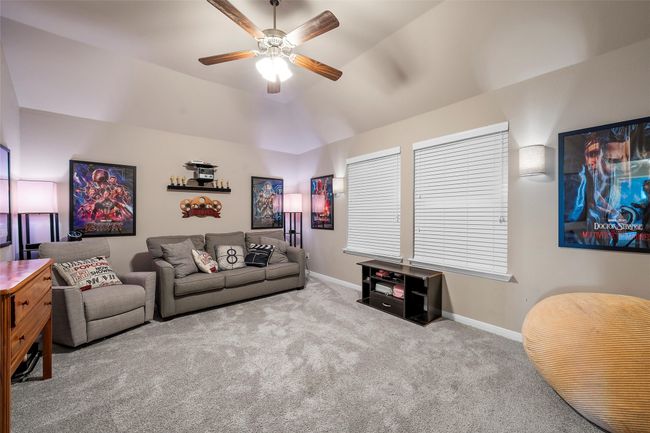 Carpeted living area featuring a ceiling fan and lofted ceiling | Image 27