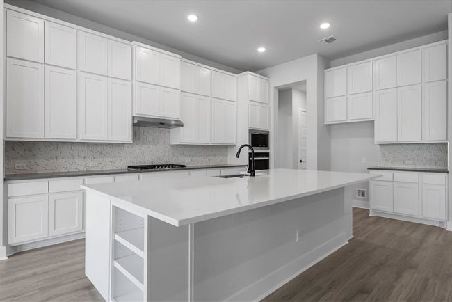 Kitchen featuring stainless steel appliances, ventilation hood, light wood-type flooring, backsplash, and recessed lighting | Image 11