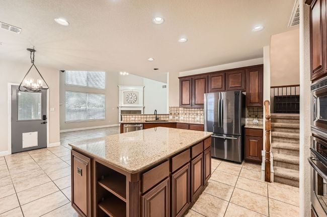 Kitchen with appliances with stainless steel finishes, a sink, decorative backsplash, light tile patterned floors, and visible vents | Image 16