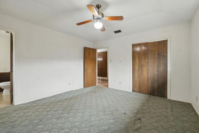 Unfurnished bedroom featuring carpet flooring, ensuite bathroom, a closet, baseboards, and a ceiling fan | Image 25