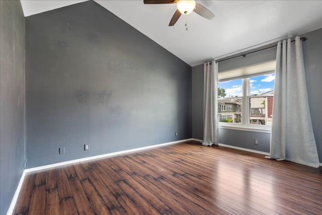 Empty room featuring ceiling fan, lofted ceiling, wood finished floors, and baseboards | Image 6
