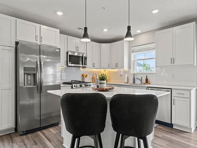 A large center island with breakfast bar seating provides additional working space and functional gathering. | Image 4