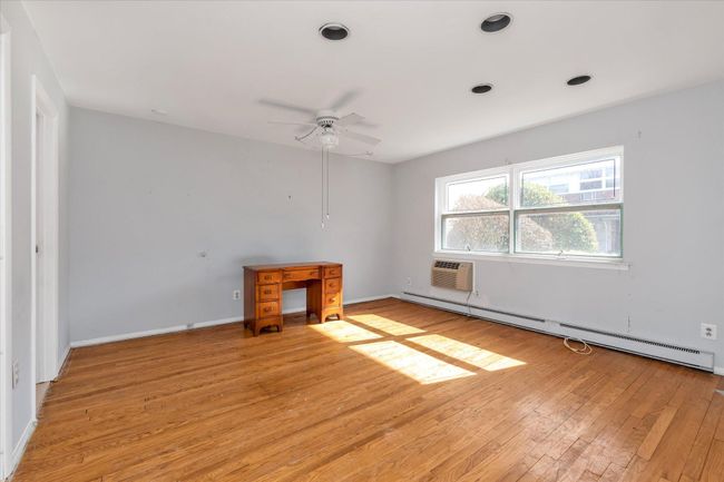 Bedroom with a ceiling fan, baseboards, baseboard heating, light wood-type flooring, and a wall mounted AC | Image 15