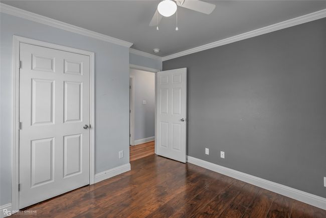 Unfurnished bedroom featuring ceiling fan, ornamental molding, dark wood finished floors, and baseboards | Image 19