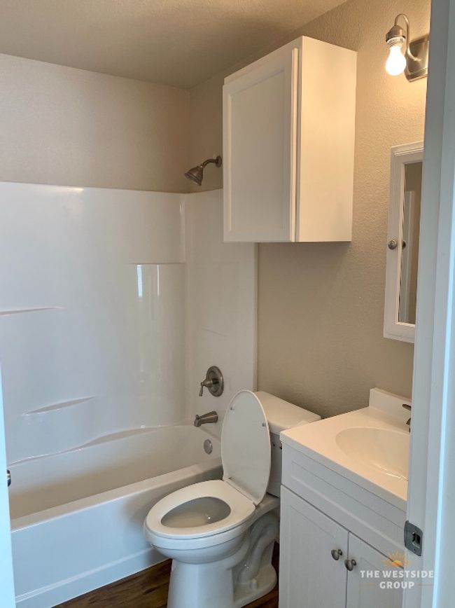 Bathroom with toilet, vanity, wood finished floors, and shower / washtub combination | Image 4