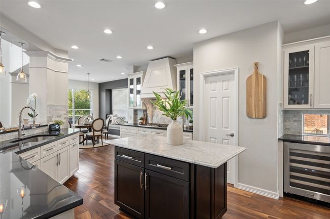 Kitchen featuring visible vents, dark stone countertops, white cabinetry, a sink, and beverage cooler | Image 4