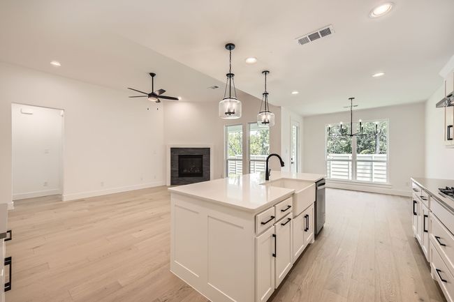 Kitchen with a fireplace, a sink, a ceiling fan, light wood finished floors, and pendant lighting | Image 13