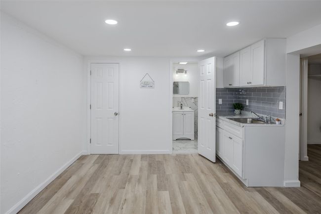 Kitchen with sink, white cabinetry, light wood-type flooring, and tasteful backsplash | Image 33
