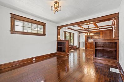 Unfurnished living room with decorative columns, a chandelier, beam ceiling, dark wood-type flooring, and coffered ceiling | Image 3