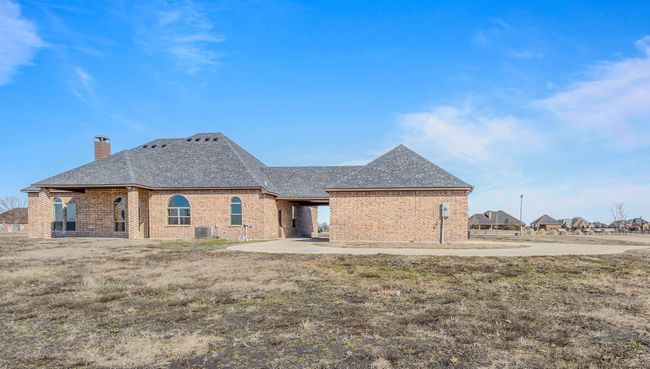 Rear view of property featuring roof with shingles, brick siding, and a chimney | Image 34