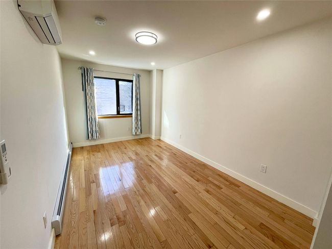 Empty room featuring baseboard heating, light hardwood / wood-style floors, and a wall unit AC | Image 6