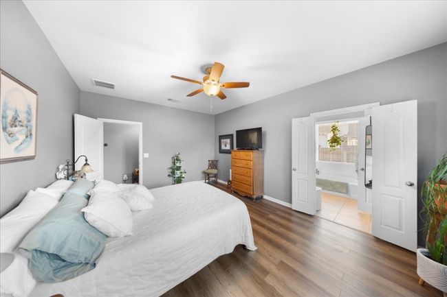Bedroom with dark wood-style floors, ceiling fan, and ensuite bath | Image 9
