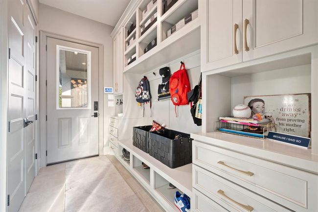 A well-organized mudroom with built-in storage, including shelves, drawers, and hooks for hanging items. The space is bright, with a door leading outside and stylish cabinetry, providing functional and attractive storage solutions. | Image 23