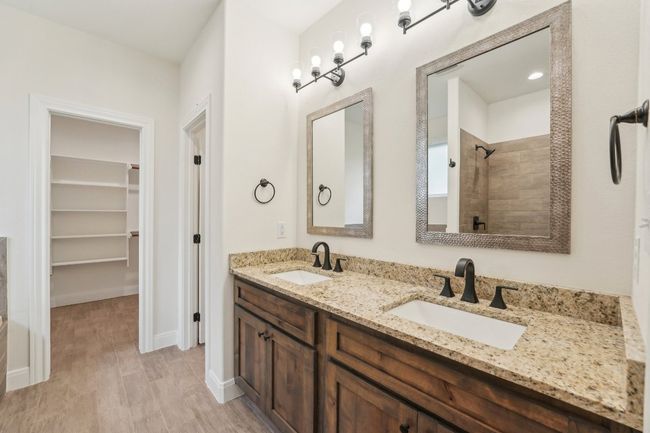 Full bath featuring a walk in closet, double vanity, tiled shower, and a sink | Image 23