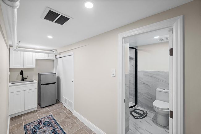 Kitchen featuring freestanding refrigerator, a sink, white cabinets, recessed lighting, and light countertops | Image 19